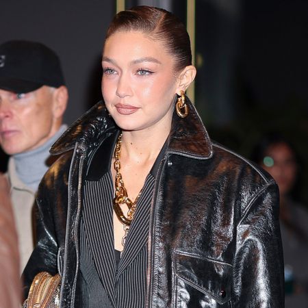 Gigi hadid wears a leather jacket, pinstripe set, and gold chain jewelry.