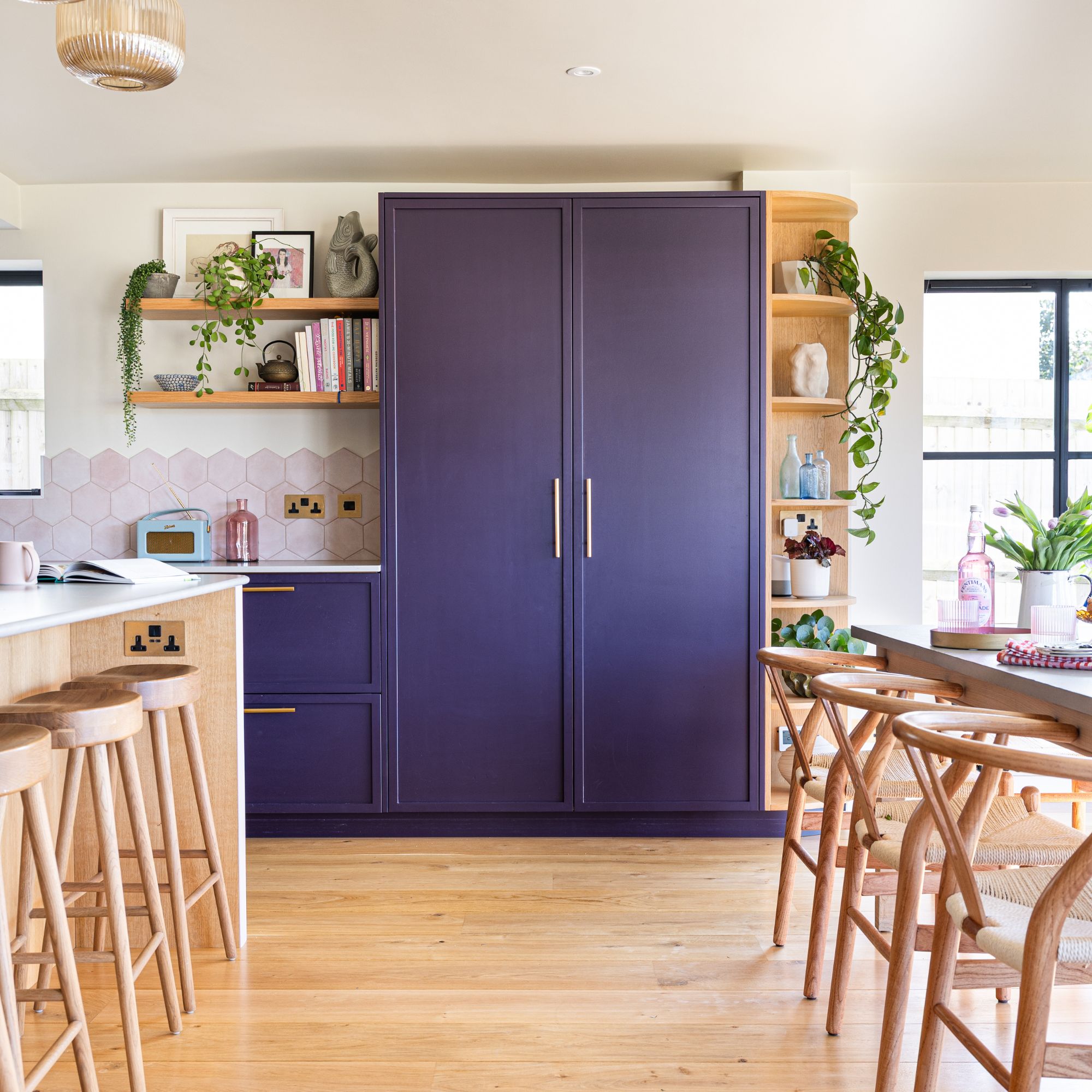 Open plan kitchen-dining room with large blue cabinets and shelves at the back of the room