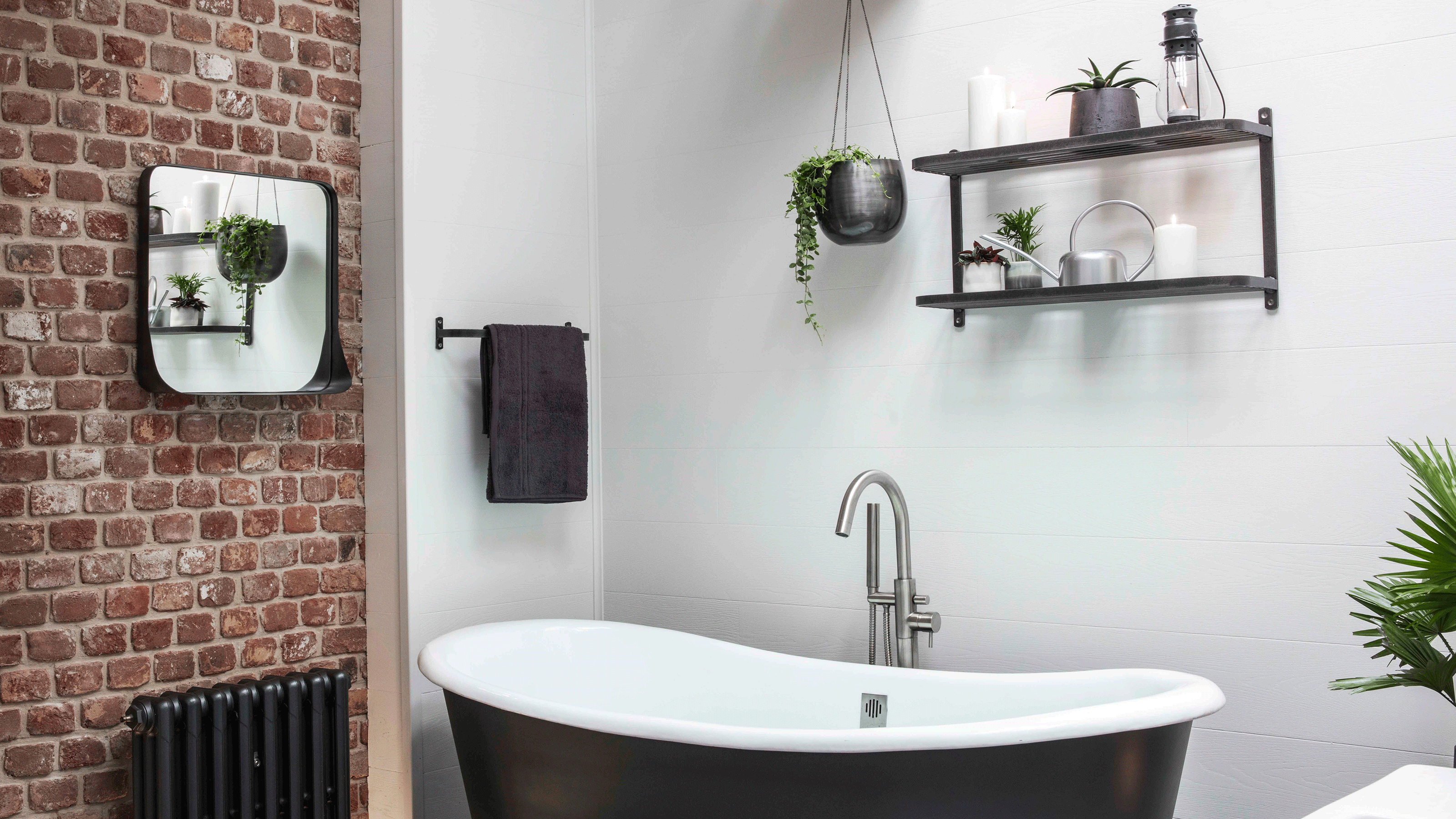 Black two-tier shelving unit above black freestanding bath tub in brick-exposed industrial bathroom