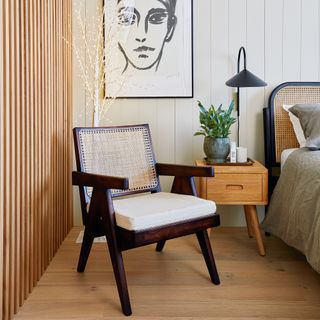 Dark wood armchair in a white bedroom with a contemporary warm wood panelled wall