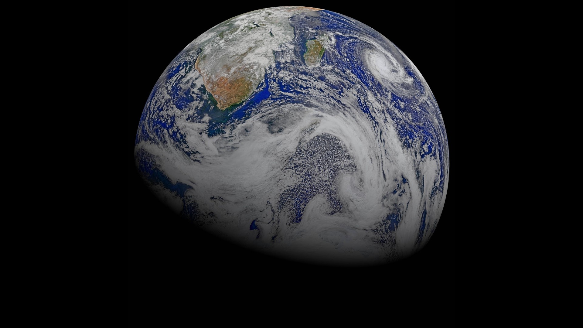 a blue planet covered in white clouds on a black, empty background