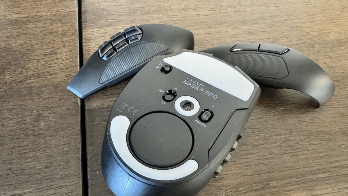 The Razer Naga V3 Pro on a wooden table from the bottom, next to its faceplates