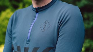 A close up of the front of a teal jersey with black details