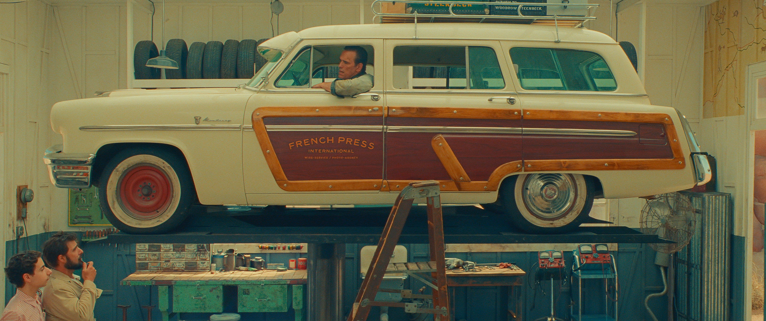 a man sits in a station wagon on a lift