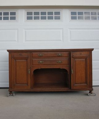 Antique wooden buffet in front of white garage