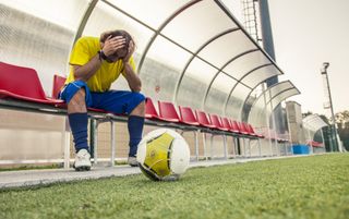 A footballer holds their head in their hands after hearing about eFootball's update delay.