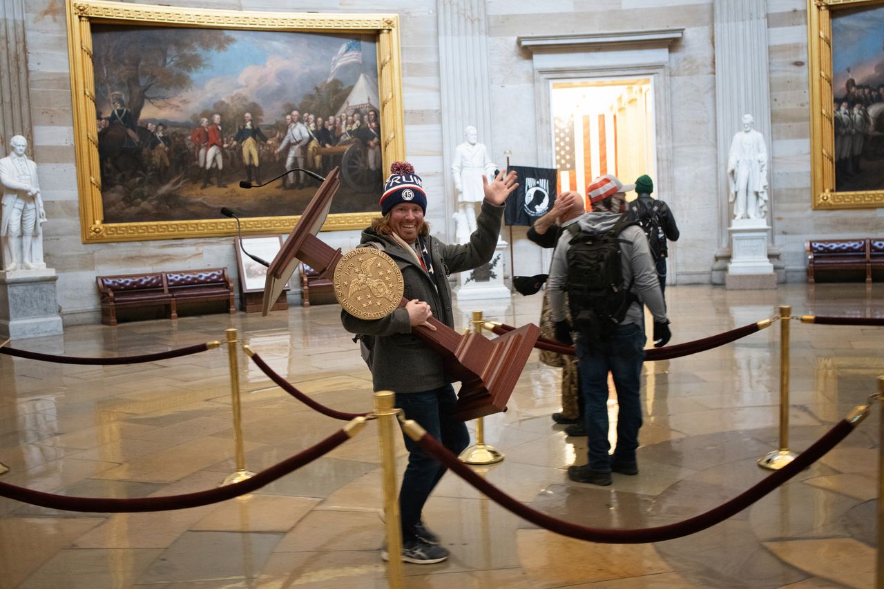 A Trump supporter from Florida carries out a lectern during the Capitol riot.