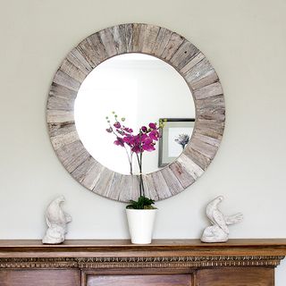 round mirror on wall with flower pot on table