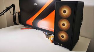 Origin Chronos V3 gamign PC with orange lights on desk