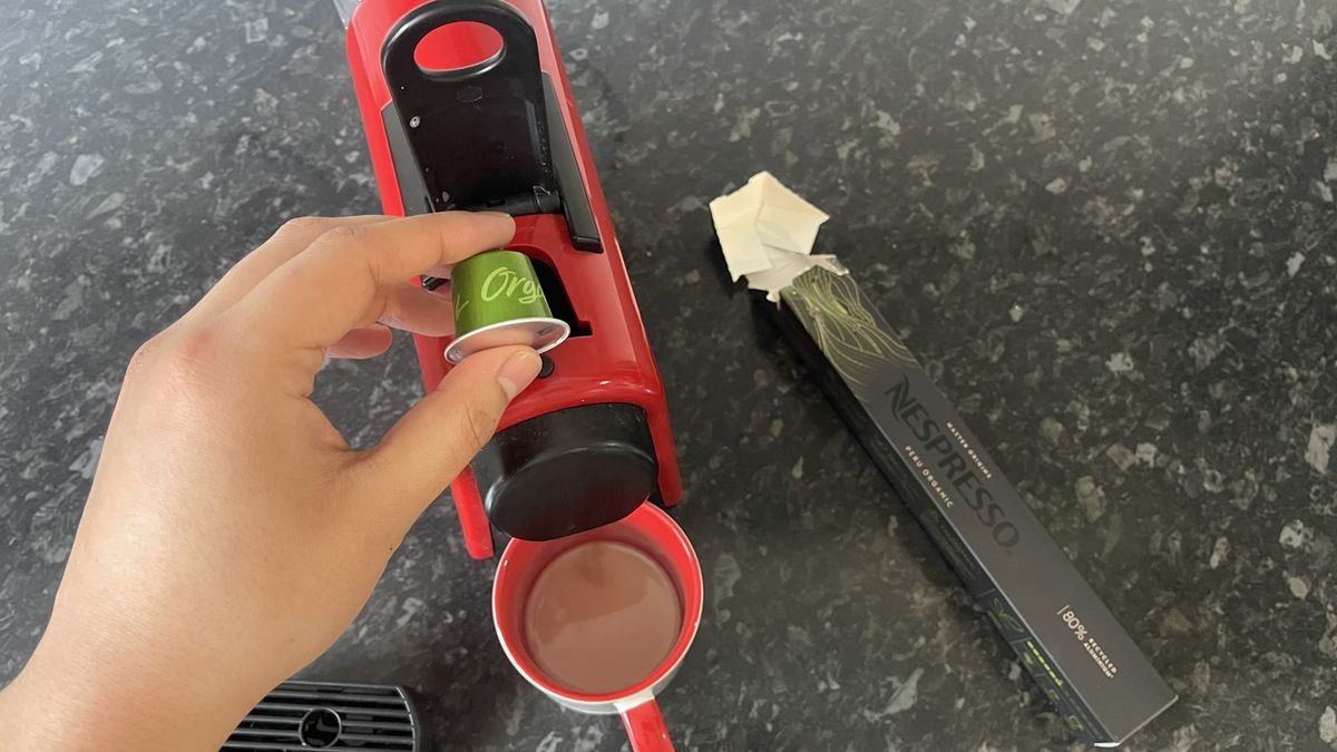 Nespresso Essenza Mini with pod held above, and drip tray removed