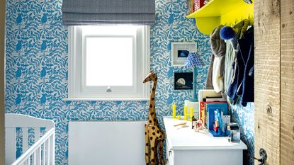 blue nursery with wallpaper, chest of drawers and shelf with hooks