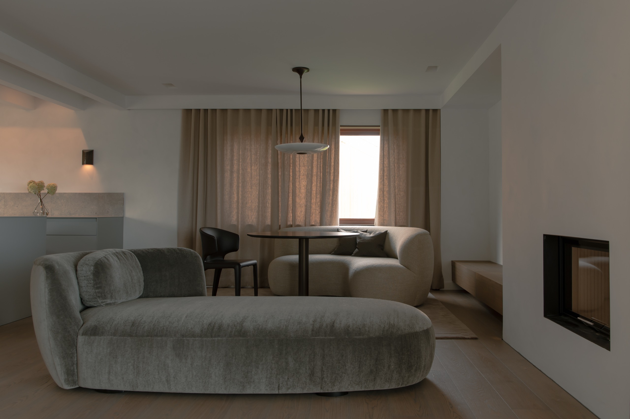 neutral toned living room with a fireplace, velvet day bed and linen curtains