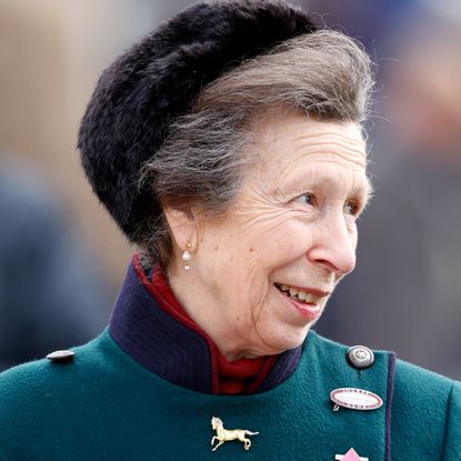 Princess Anne wearing a green coat and fur hat smiling 