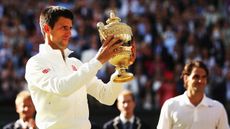 Novak Djokovic poses with the Gentlemen's Singles Trophy after defeating Roger Federer