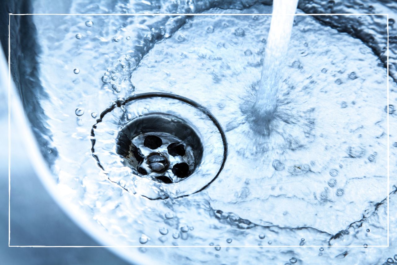 Water from the tap flowing into the plug of a stainless steel kitchen sink