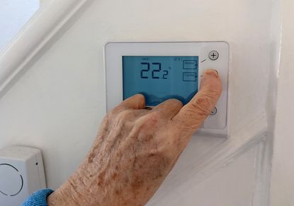 Person turning down the central heating with a wireless thermostat