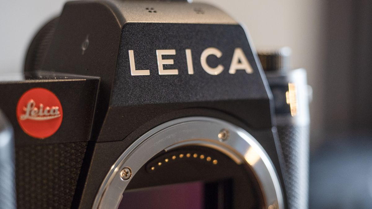 Leica SL3 camera on a wooden surface against a blue background