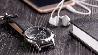 Rotary watch on a table with wired headphone and notepad