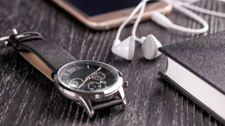 Rotary watch on a table with wired headphone and notepad