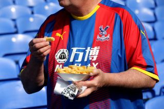 A Crystal Palace fan in the stands with a tray of chips before the Premier League match at Selhurst Park, London