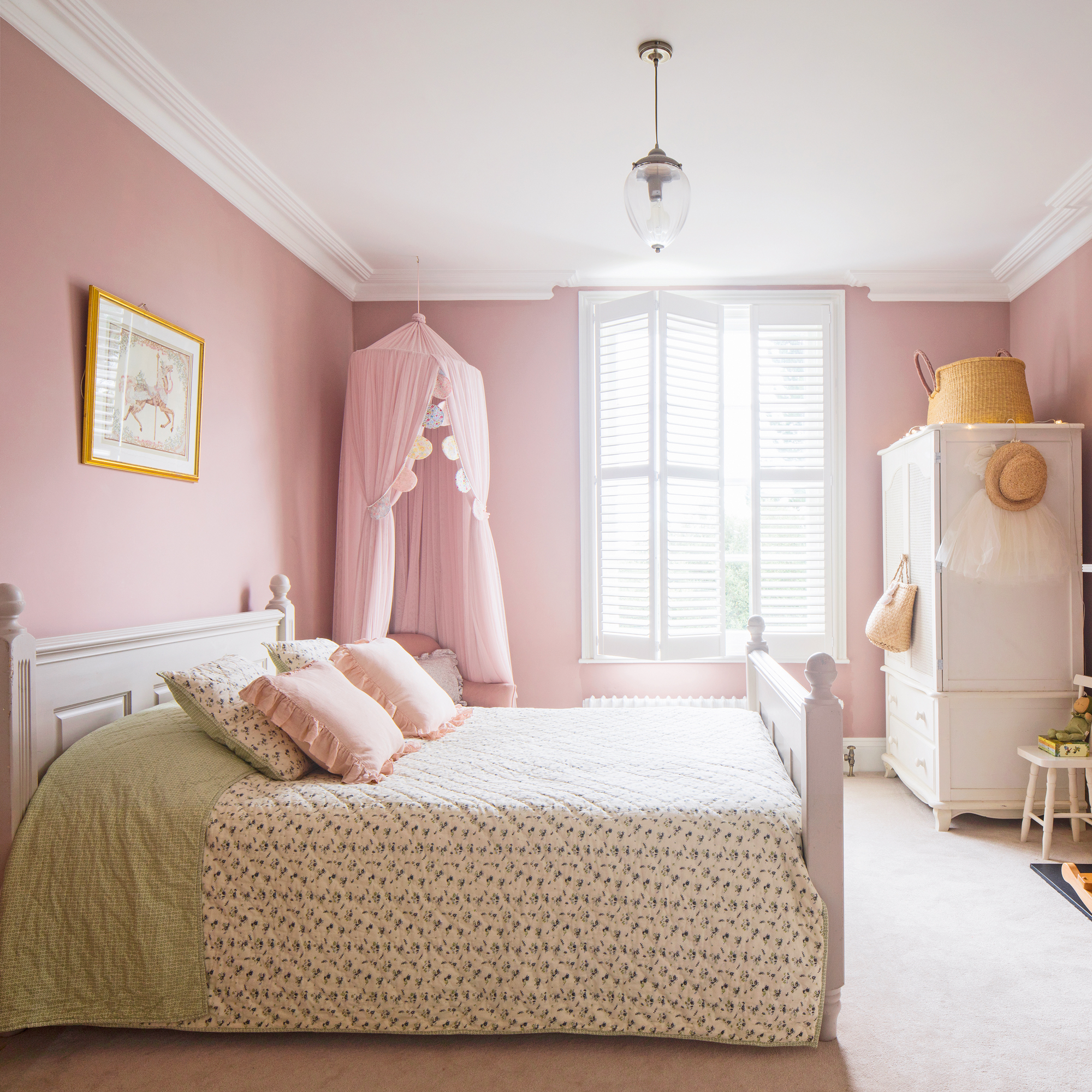 a child's pink bedroom with a canopy tent around a pink armchair and shuttered windows