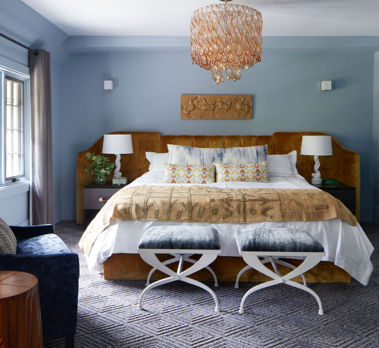 Orange velvet headboard and bed base blue walls, armchair and cushions
