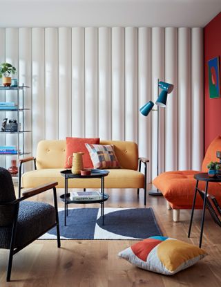 a living room with earthy tone furniture including a terracotta orange armchair, ochre sofa and a black coffee table with accessories