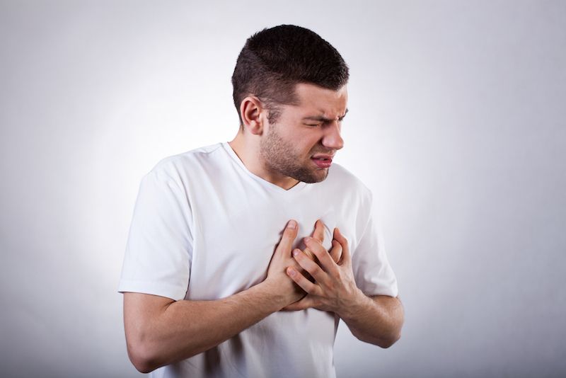 A young man clutches his chest in pain.