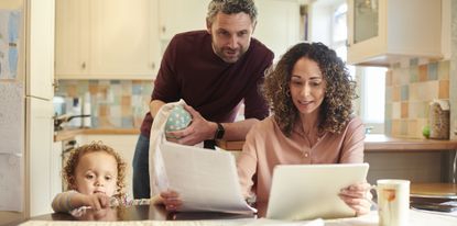 Man woman and child gathered around table looking at papers and tablet