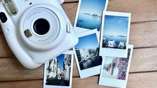 Fujifilm Instax mini 11 camera on a table, surrounded by instant photos.