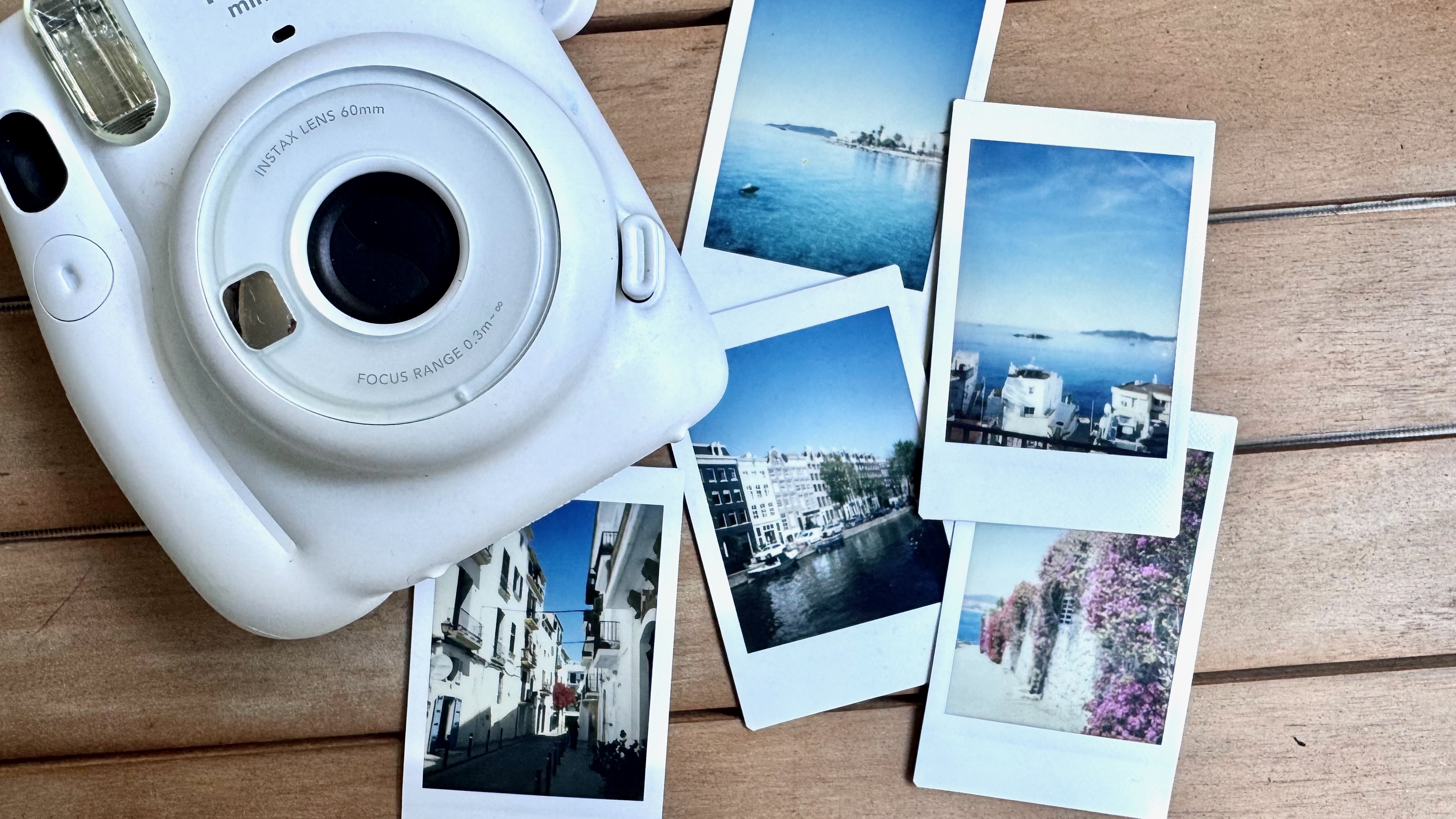 Fujifilm Instax mini 11 camera on a table, surrounded by instant photos.