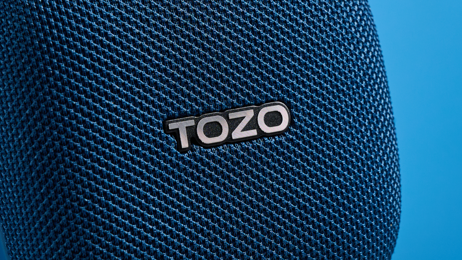Tozo PE1 speaker in blue with built-in clip photographed on a blue background.