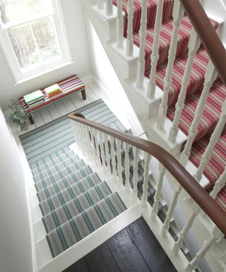 Staircase with green and red stair runners across different levels of home by Roger Oates