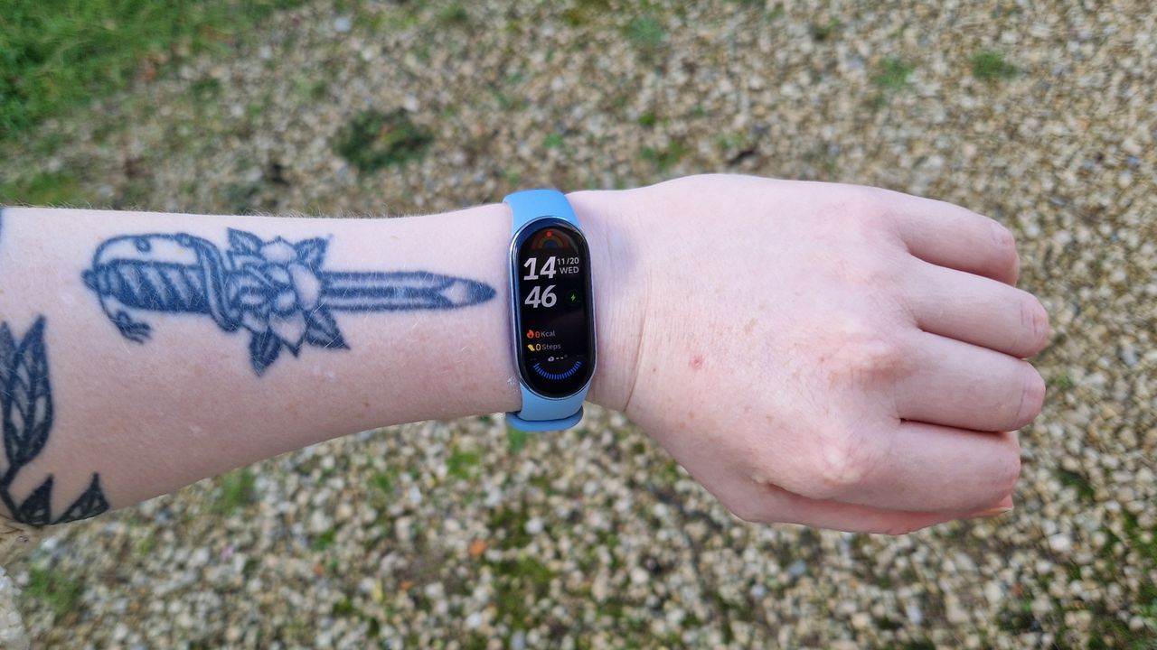 Forearm and wrist with blue fitness tracker on it. The time on the tracker reads 14:46