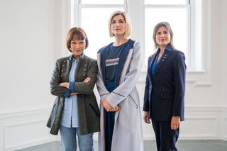 A posed in-character on-set shot of Tegan Jovanka (Janet Fielding), the Doctor (Jodie Whittaker) and Ace (Sophie Aldred), all facing the camera