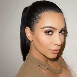 Kim Kardashian with her hair tied back in a sleek ponytail.