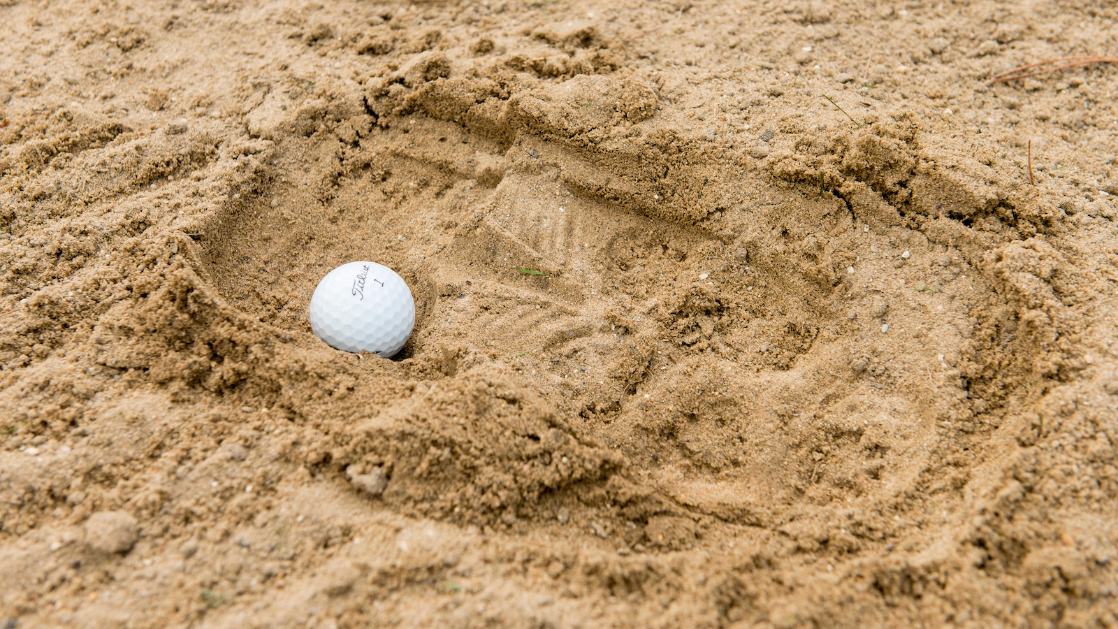 A ball in a footprint in an unraked bunker