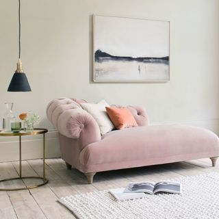 living room with white wall pink chaise longue with cushion and wooden flooring