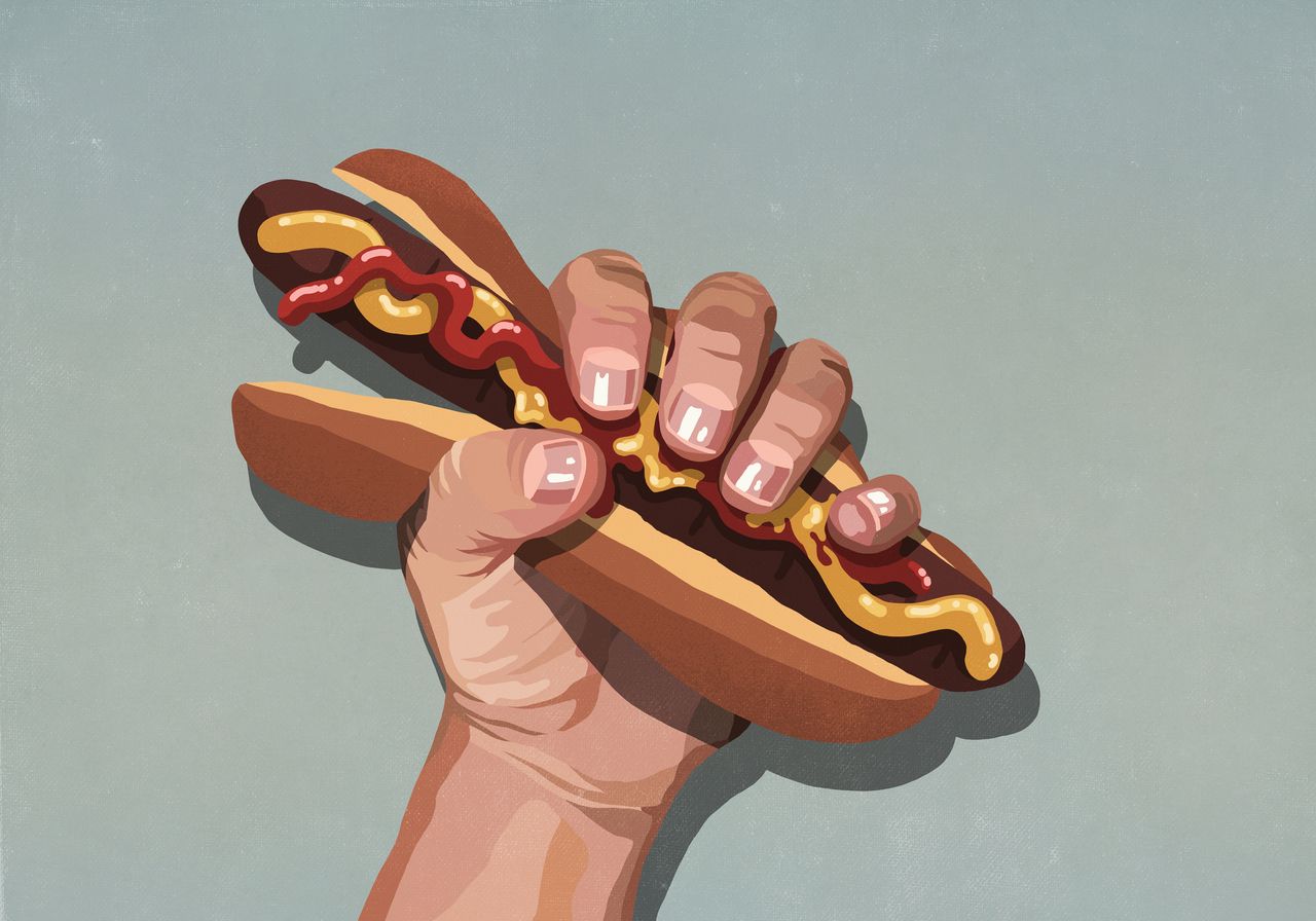 Mans hand squeezing hot dog 