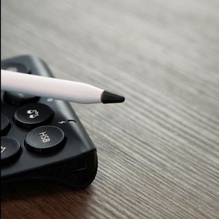 Apple Pencil with black tip resting on a calculator