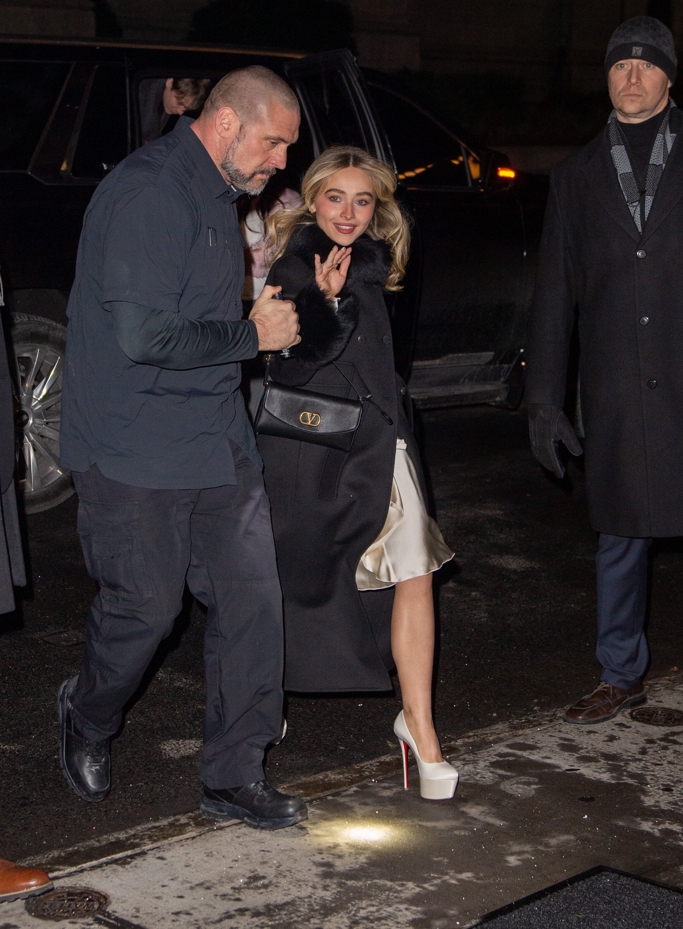 Sabrina Carpenter is seen on January 17, 2026 in New York City wearing a black fur-trimmed coat, a silky slip dress, and platform Christian Louboutin heels