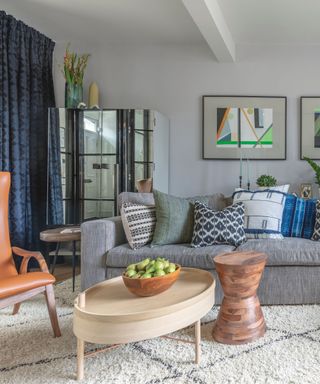 A gray living room with patterned drapes, abstract artwork, and patterned throw pillows