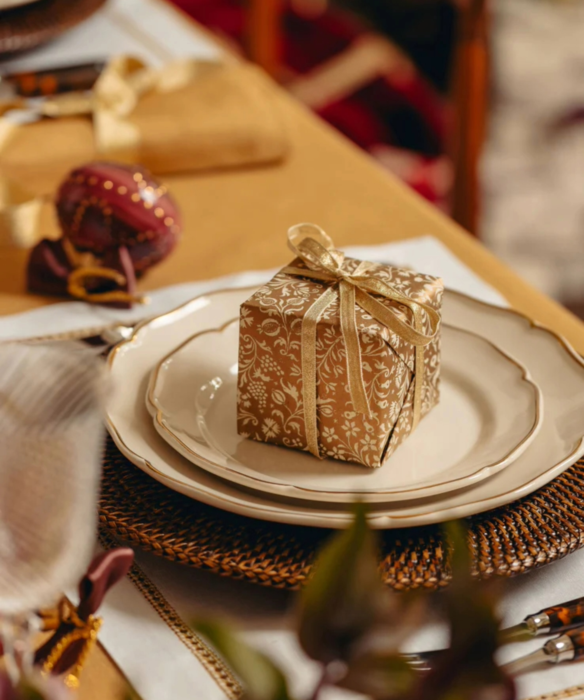 Gold wrapped gift on white plates on a Christmas table