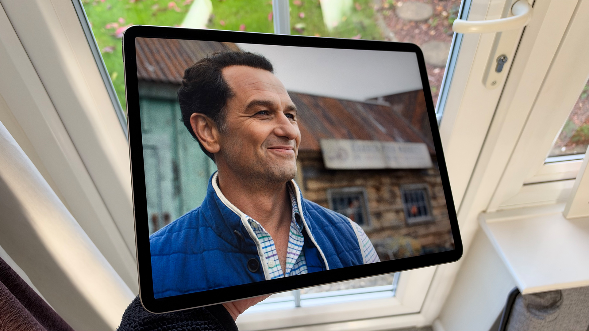 Apple iPad Air 13-inch (M4) tablet held in front of door, on screen is Matthew Rhys