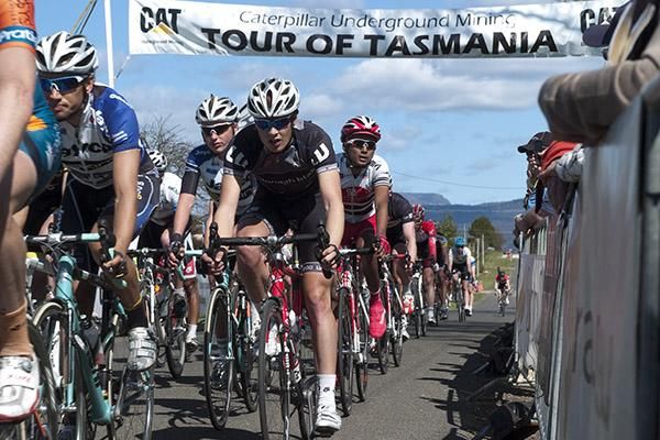 The peloton make their way beneath the banner in Westbury on the final day of the tour.