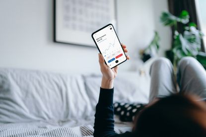 Person in bed looking at investments on mobile