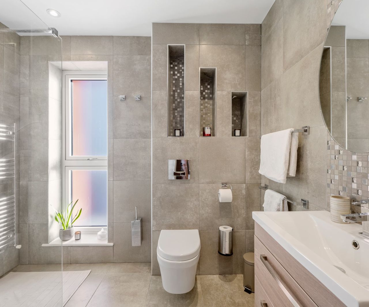 A wall toilet with indents in the wall behind for candles