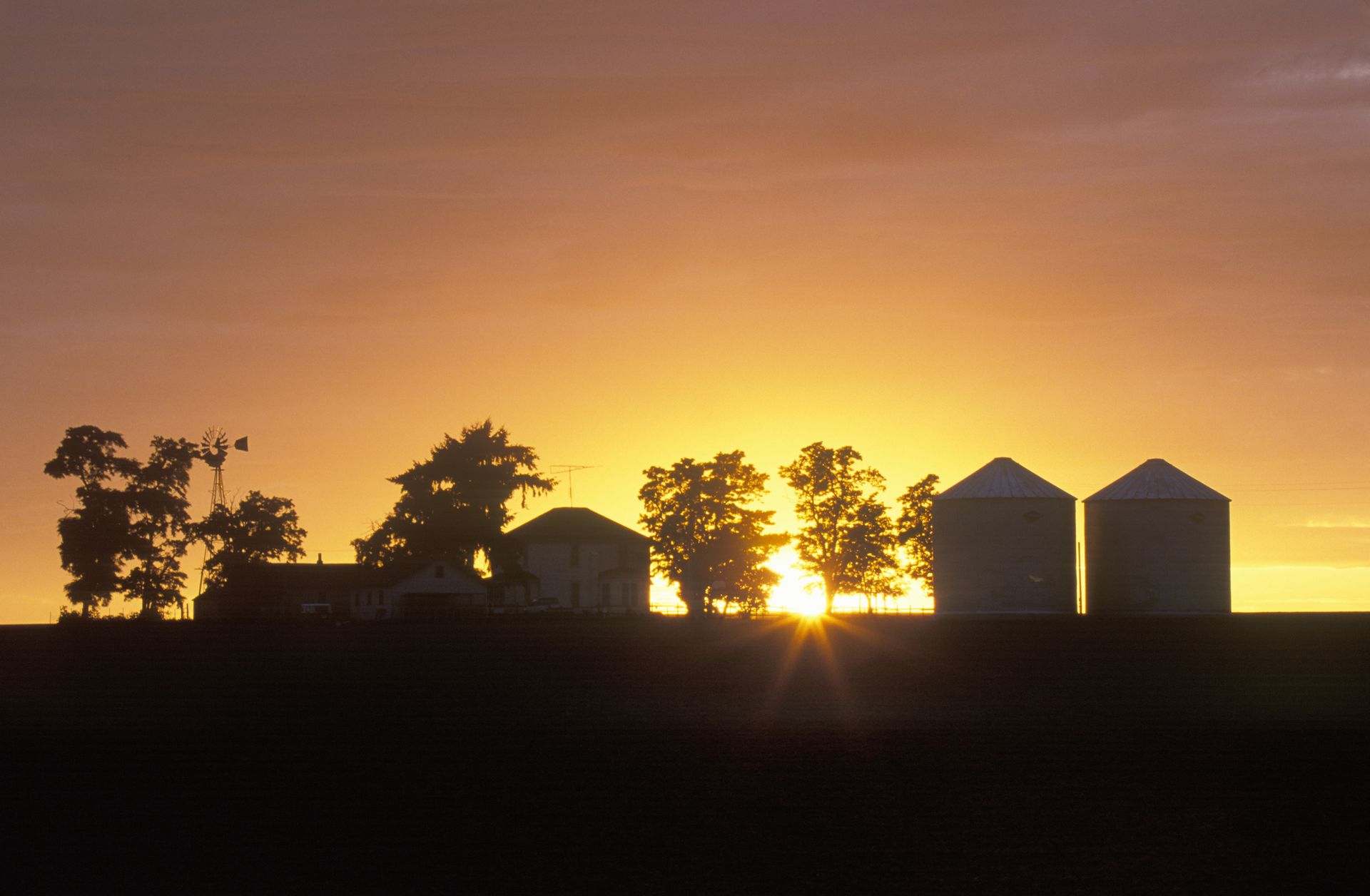 silhouette of a farm and outbuildings against a sunset in Ritzville, Washington