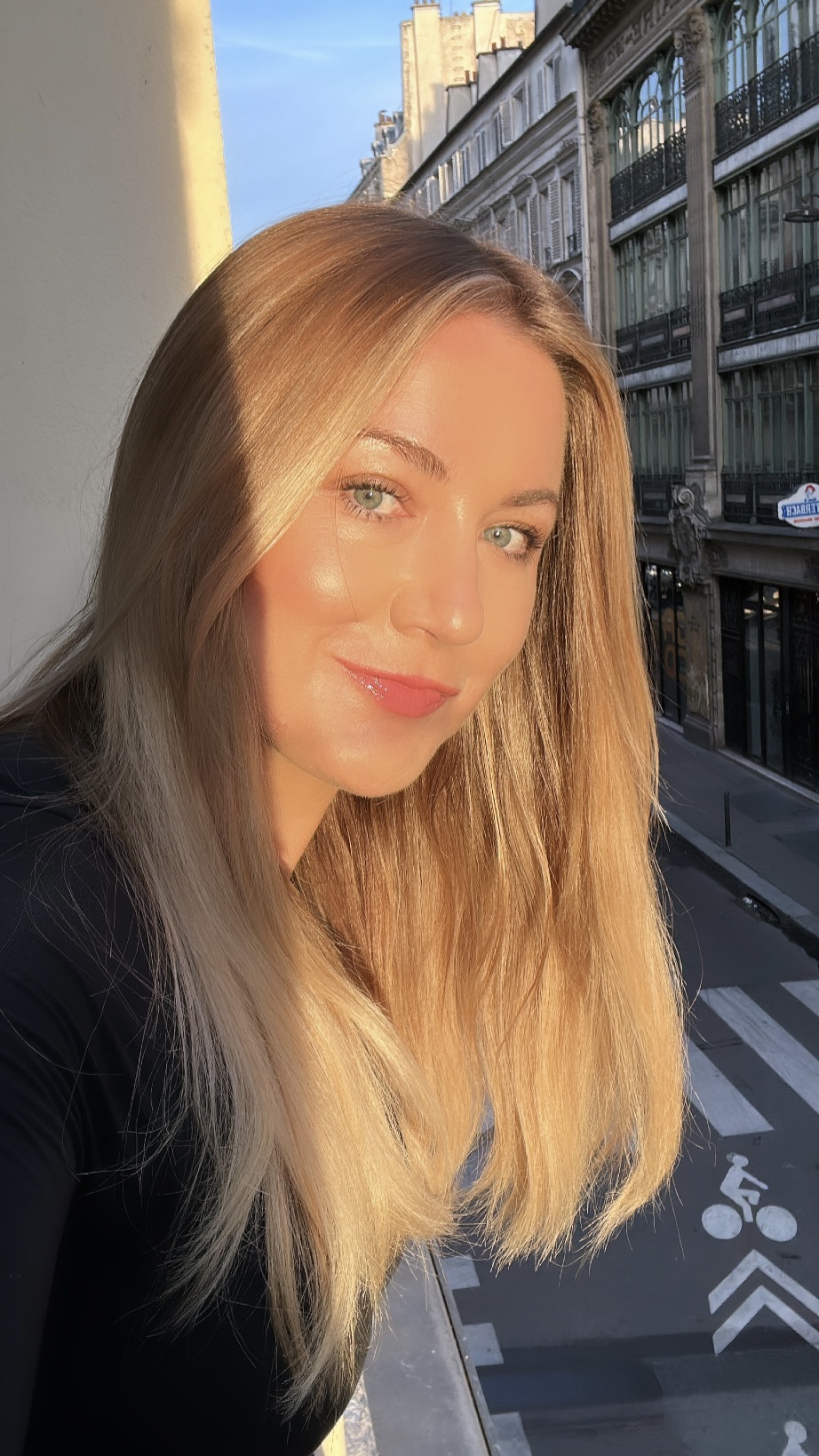 a blonde woman in the sunshine on a Paris balcony