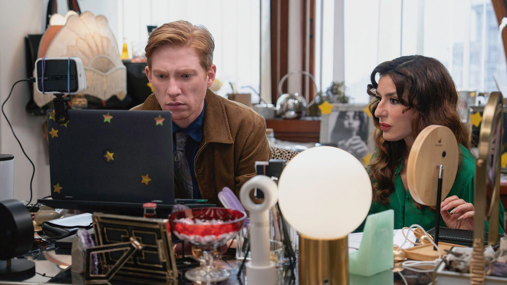 L-R: Ned (Domhnall Gleeson) and Esmeralda (Sabrina Impacciatore) sitting at a computer desk in a scene from &quot;The Paper&quot;